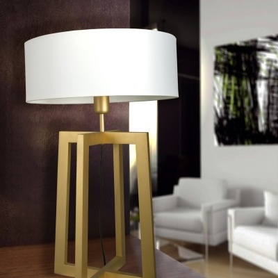 Candeeiro de mesa com base dourada geométrica e abajur branco numa sala