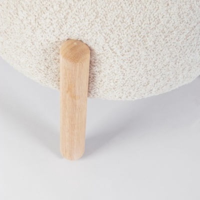 Pé de madeira clara unido a tecido bouclé branco texturizado de um móvel
