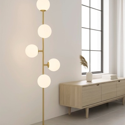 Lâmpada de pé com globos brancos e estrutura dourada junto a móvel de madeira clara