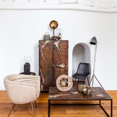 Sala com cadeira estofada bege, armário e mesa de centro castanhos, cadeira preta e candeeiro de pé metálico