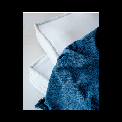 Almofadas brancas empilhadas com manta azul texturada