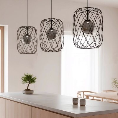 Candeeiros de teto metálicos pretos entrelaçados com lâmpadas esféricas escuras suspensos sobre mesa de cozinha clara com bonsai e copos.