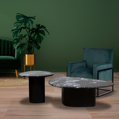 Duas mesas de centro de mármore com bases negras, poltrona azul, planta em vaso dourado, parede verde, chão madeira.