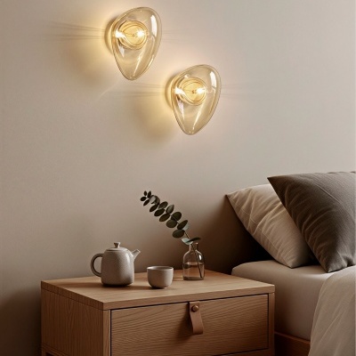 Mesa de cabeceira em madeira clara com bule, chávena e vaso, e lâmpadas de parede em vidro amarelo