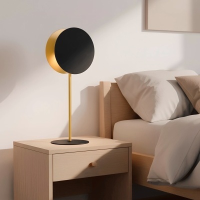 Candeeiro moderno preto e dourado sobre mesa de cabeceira de madeira clara ao lado de cama