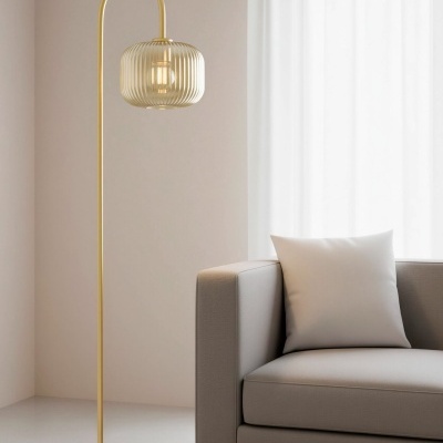 Candeeiro de pé dourado com cúpula de vidro ao lado de sofá cinzento claro com almofada branca