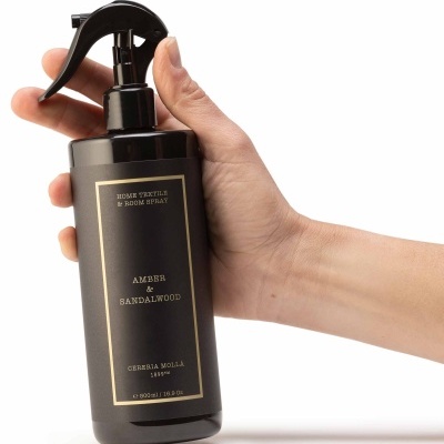 Frasco preto com pulverizador e etiqueta dourada de spray para casa e ambiente