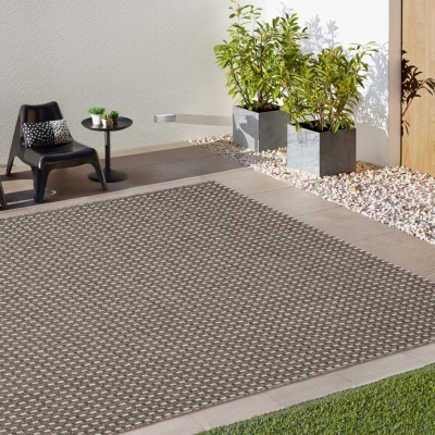 tapete exterior cinza com padrão geométrico ao lado de plantas em vasos e cadeira preta