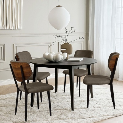 Mesa de jantar redonda preta com quatro cadeiras castanhas e decoração numa sala clara