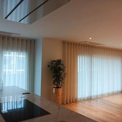 sala moderna com cortinas brancas translúcidas e bancada de cozinha em mármore cinzento