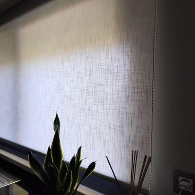 Estores brancos translúcidos com textura, planta e difusor numa janela