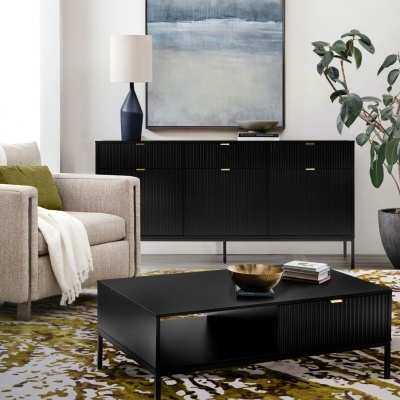 Sala de estar com móvel preto, mesa de centro, sofá bege, candeeiro azul e quadro abstrato azul