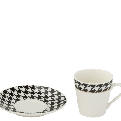 Chávena de café branca com padrão pied-de-poule preto e branco e pires à sua frente