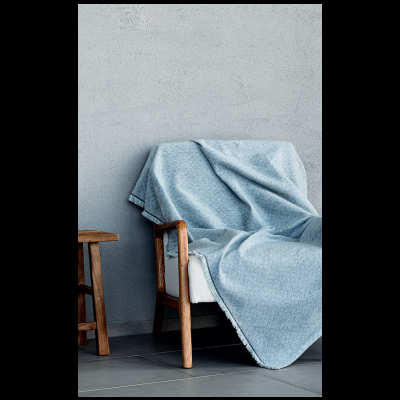 Cobertor azul claro sobre cadeira de madeira com almofada branca junto a banco de madeira