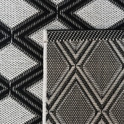 Detalhe de tecidos com padrões geométricos em preto e branco sobrepostos.