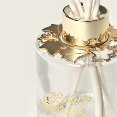 Frasco de vidro transparente com tampa dourada e palitos brancos