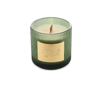 Vela perfumada em copo de vidro verde com etiqueta dourada