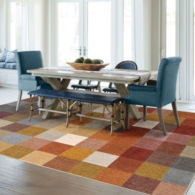 Mesa de madeira com cadeiras azuis e banco azul escuro sobre tapete colorido quadriculado