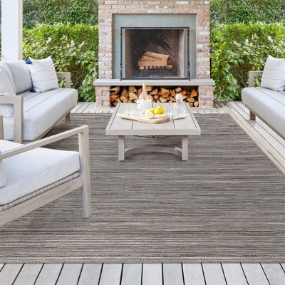 Conjunto mobiliário exterior madeira clara almofadas cinza lareira tijolos tapete cinza riscas