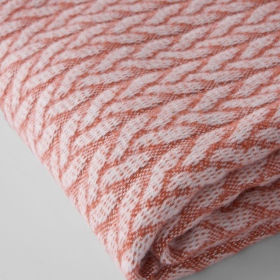 Manta dobrada com padrão geométrico branco e laranja