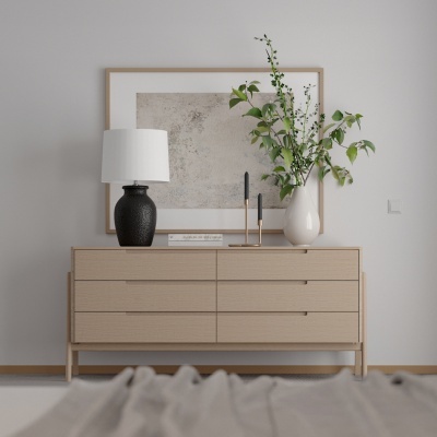 Cómoda de madeira clara com candeeiro preto, vaso branco com ramo verde e arte abstrata cinzenta