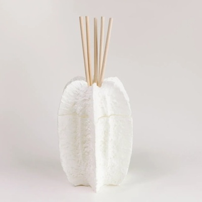 Difusor de ambiente branco com varetas de madeira sobre fundo cinza claro