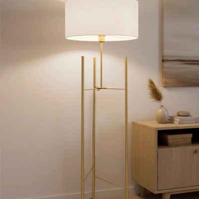 Candeeiro de pé dourado com abajur branco num quarto moderno