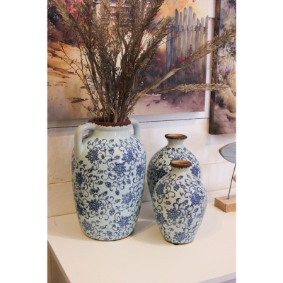 Três vasos de cerâmica branca com padrão floral azul, decorados com ramos secos