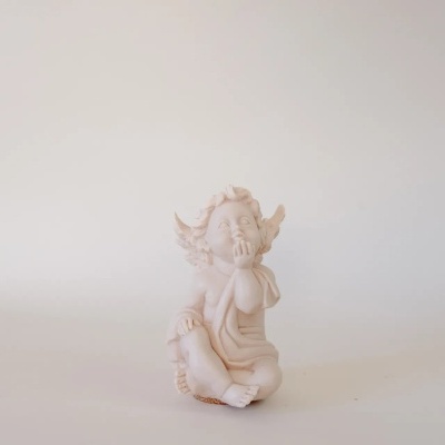 Estatueta branca de anjo sentado com asas e expressão pensativa