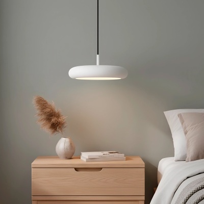 Mesa de cabeceira em madeira com vaso e candeeiro suspenso branco junto a cama com almofadas e roupa de cama