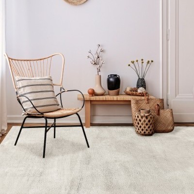 Cadeira de metal e madeira com almofada, banco de madeira, vasos decorativos e cestos de palha num interior