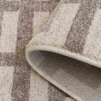 Tapete riscado em bege, castanho e branco com bordas costuradas