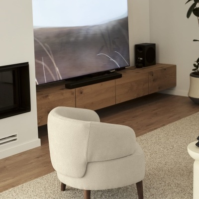 cadeira bege claro com pernas em madeira escura num ambiente interior com televisão e móvel de madeira