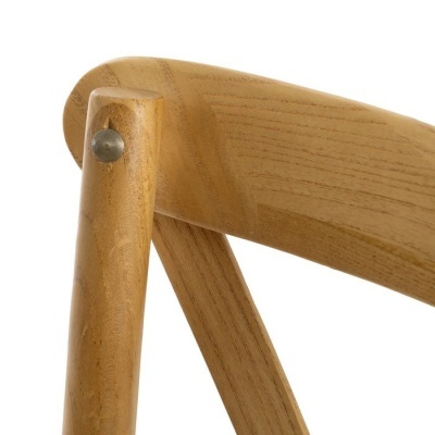 Detalhe de cadeira de madeira clara com encosto curvo e parafuso metálico