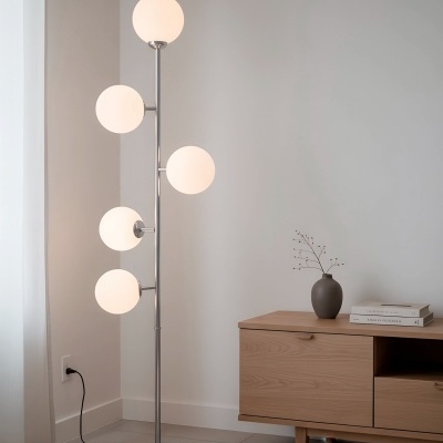 Luminária piso com globos de vidro fosco e estrutura metálica prateada ao lado de móvel em madeira clara com decoração