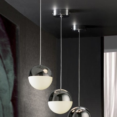 Três candeeiros pendentes cromados esféricos com metade opaca suspensos em tecto escuro