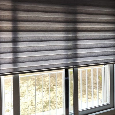 Estores cinzentos lisos em janela branca com porta deslizante e grade exterior