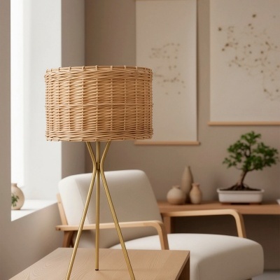 Candeeiro com abajur de vime e base dourada numa mesa de madeira junto a poltrona branca e decoração minimalista