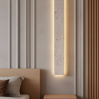 Luminária de parede retangular branca texturada com iluminação quente ao lado de cama e mesa de cabeceira em madeira clara