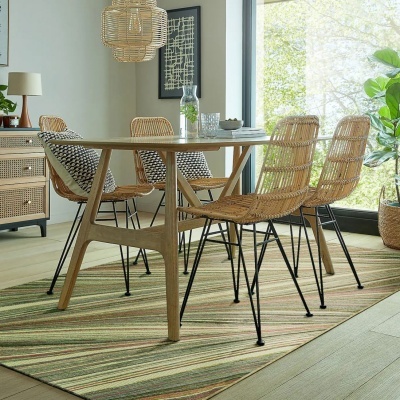 Mesa de madeira clara com quatro cadeiras de rattan natural e moldura metálica preta numa sala clara