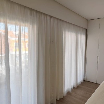 Cortinas brancas transparentes e opacas num quarto com chão de madeira clara