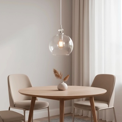 Mesa de jantar redonda em madeira clara com cadeiras bege, vaso decorativo, pendente de vidro e cortinas brancas