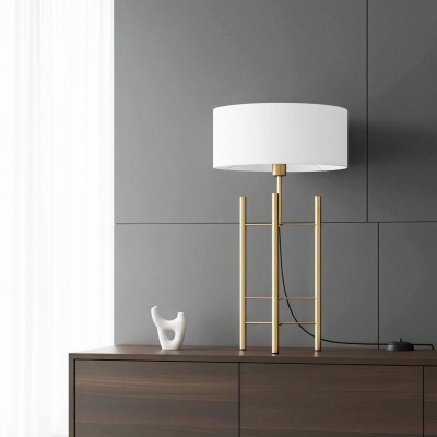 Candeeiro de mesa dourado com abajur branco sobre móvel de madeira escura