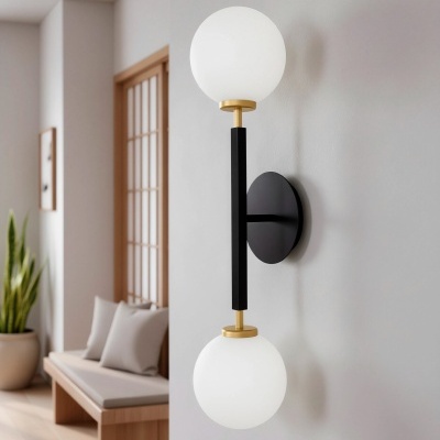 Aplica de parede com duas esferas de vidro opaco branco, estrutura preta e dourada, instalada numa parede branca em interior moderno.