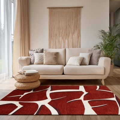 Tapete vermelho e branco com padrão abstraído geométrico na sala com sofá bege e almofadas.