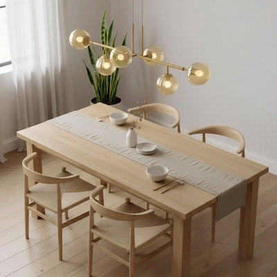 Mesa de jantar em madeira clara com cadeiras, louça branca e lustre dourado