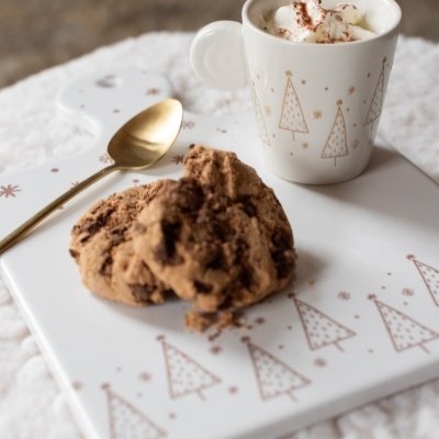 Caneca branca decorada com árvores douradas, cookies e colher dourada