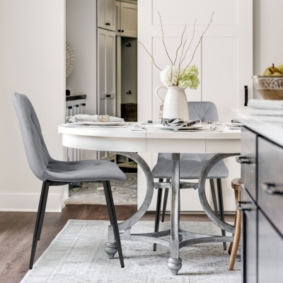Mesa de jantar branca com base em metal e duas cadeiras cinza estofadas