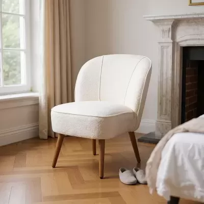 Cadeira branca estofada com pernas de madeira numa sala ao lado de chinelos