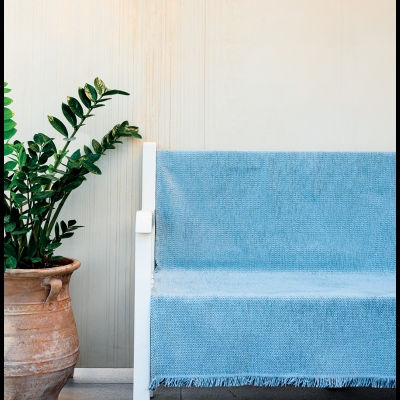 Banco branco com manta azul e vaso cerâmico com planta verde